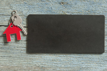 blank blackboard and symbol of the house with silver key on vintage wooden background