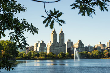 Blurred New York City Manhattan Central Park panorama, lake with fountain and skyscrapers on...