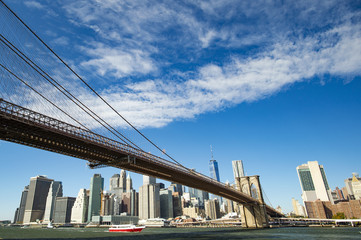 Manhattan skyline with the Brooklyn bridge and the One World Trade Center in the background during a sunny day in New York, USA.