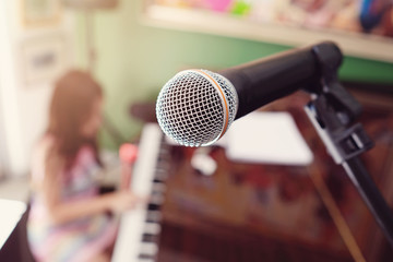 microphone with blurred little girl playing piano background, homeschool music education