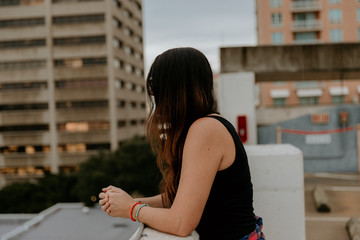 Cute Dark Haired Female Model Posing in Ripped Jeans and Plaid Shirt on Top Floor of Parking Garage