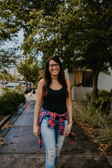 Cute Dark Haired Female Model Posing in Ripped Jeans and Plaid Shirt on Top Floor of Parking Garage