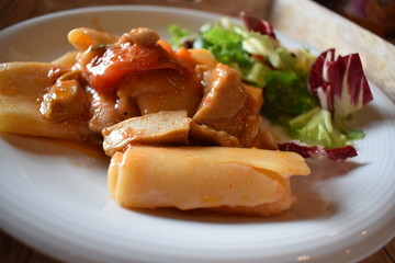 Pasta with meat tomato sauce and salad of green vegetables on a white plate