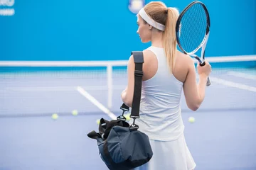 Tuinposter Back view portrait of beautiful blonde woman entering tennis court for practice, copy space © Seventyfour