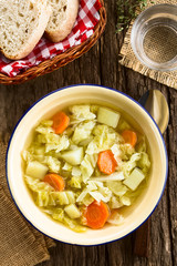 Fresh homemade vegan cabbage soup with carrot and potato served in bowl, photographed overhead (Selective Focus, Focus on the dish)