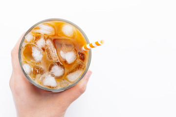 Ice latte top view close up on white background and clipping paths. With copy space. A woman's hand holds a glass of cold coffee