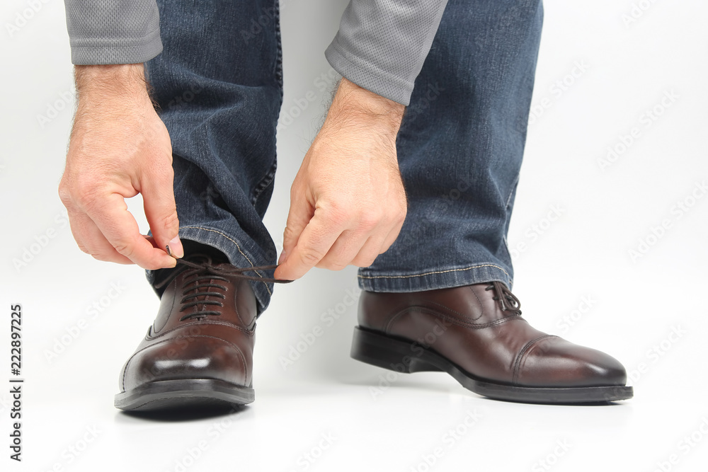 Wall mural man tying shoelaces on classic brown oxford shoes