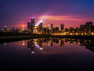 Beautiful long exposure Chicago night skyline photo with building lights at sunset with pink purple...