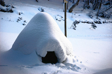 A homemade igloo near a lamp-post. The top of the igloo is pointed, and the landscape is covered in...