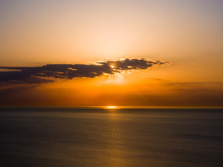 Beautiful sunrise photograph with vibrant orange and yellow colors over the dark waters of Lake Michigan in Chicago with layers of clouds in the sky above.