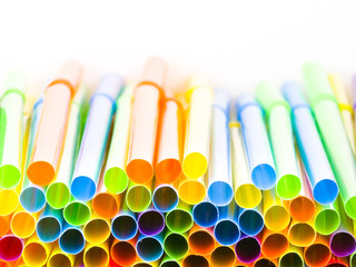Closeup photograph of the ends of numerous multi colored neon bendy flexible straws including red, green, yellow, orange, blue, and purple making a vivid, vibrant, saturated and fun background image.