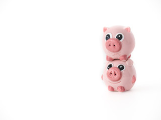 Funny close up photograph of two pink round pig ceramic salt and pepper shakers piggy backing or stacked on one another isolated on a white background with space around the animal shaped objects.
