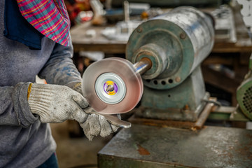 Closeup angle Grinder hand holding and Grinding the spare parts of metal gear in lathe metalworking factory, industry concept