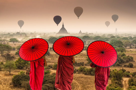 Back side of three Buddhist novice are walking over the Ancient Temples in Bagan with hot air on the sky at sunrise time, Myanmar