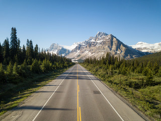 Aerial view of a scenic road in the Canadian Rockies during a vibrant sunny summer day. Taken in Icefields Parkway, Banff, Alberta, Canada.