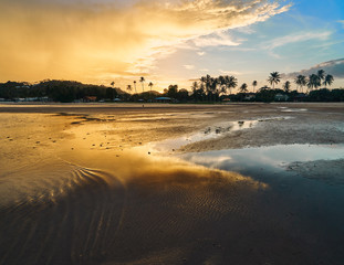 Sandy beach and palm trees on the background of the colourful sunset sky on a tropical island
