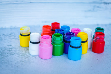 colorful Gouache or acrylic paints in jars on white grunge background, selective focus