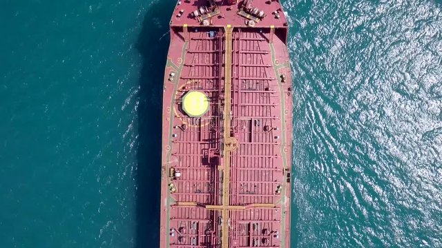 Aerial footage of a large crude oil tanker approaching a commercial port at the Mediterranean sea.