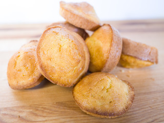 Closeup photograph of a pile of warm and delicious golden brown cornbread muffins on a butcher block counter.