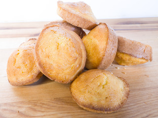 Closeup photograph of a pile of warm and delicious golden brown cornbread muffins on a butcher block counter.