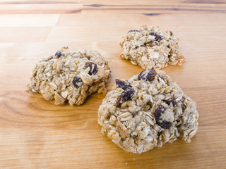 Closeup photograph of three warm fresh homemade oatmeal raisin cookies on a butcher block background.