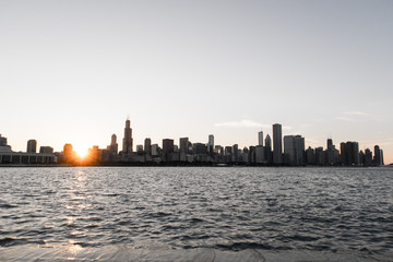 Obraz premium Chicago skyline picture during beautiful sunset with building silhouettes and rippling waves of Lake Michigan water in the foreground