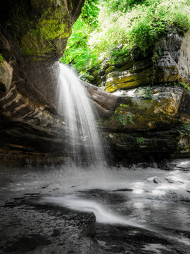 Photo of waterfall as it pours over the edge of a limestone cliff edge in the LaSalle canyon in Starved Rock State Park in Illinois
