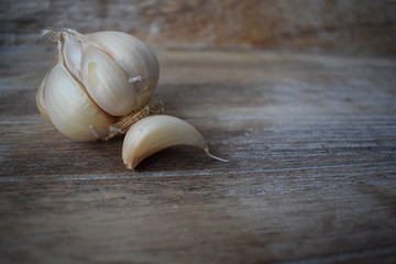 Uncleaned garlic heads with roots and stems on a wooden painted light background. Copy space.