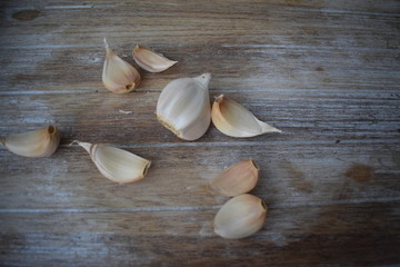 Uncleaned garlic heads with roots and stems on a wooden painted light background. Copy space.
