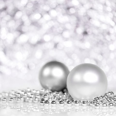 Christbaumkugeln und Perlen in Silber und Weiß, glitzernder Hintergrund