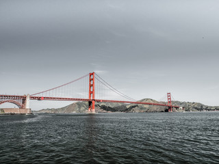 Golden Gate bridge with waves crashing against rocks in the foreground along the San Francisco Bay in California.