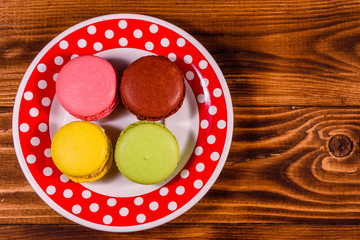 Plate with french macaroons on rustic wooden table. Top view