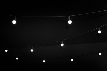 Garland with Group of Bright Bulbs in Dark, Hanging from Ceiling. Minimal Details