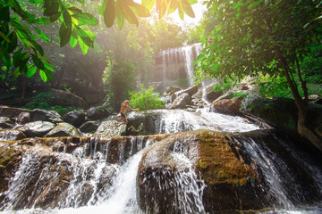 Boy is jumping into a waterfall in forest at Soo Da Cave Roi et Thailand