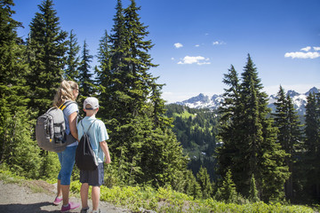 Fototapeta na wymiar A mother and son hiking together on a beautiful scenic mountain trail at Mount Rainier National Park in Washington USA
