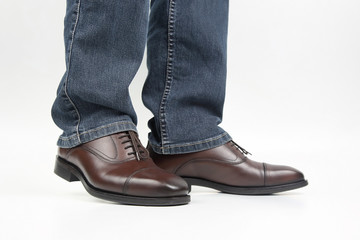 Men's legs in jeans shod in classic brown Oxford shoes