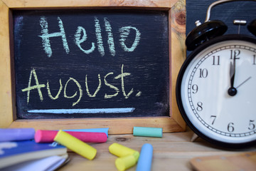Hello august. Back to school concept. Alarm clock on wooden with blackboard on background © syahrir