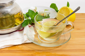 Herbal tea in glass cup against of teapot and ingredients