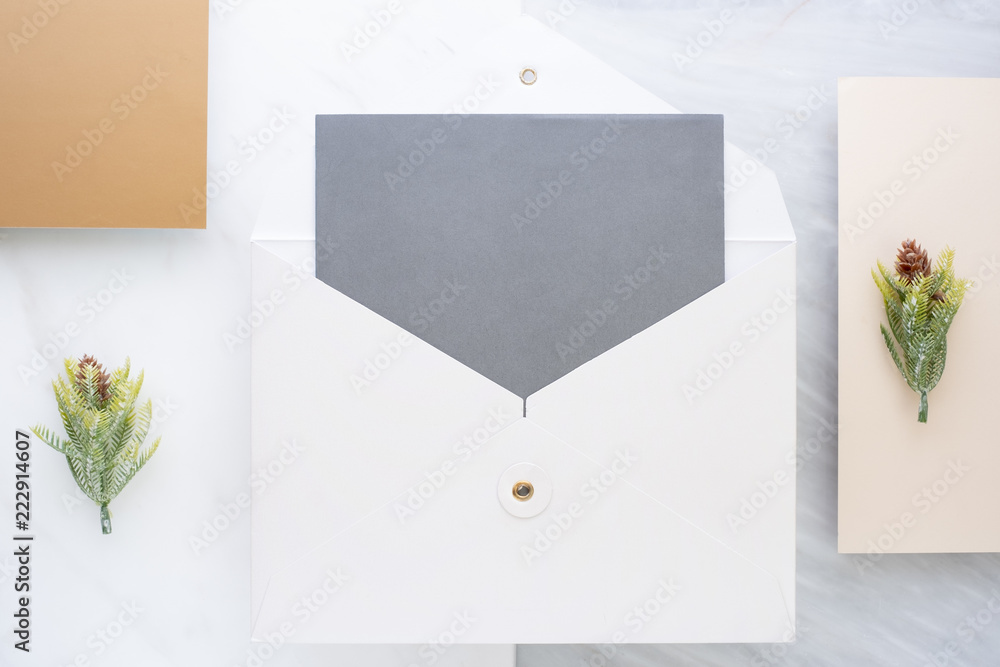 Poster Top view of blank grey card in white envelop with pine leaf on two layer step of marble table top.Mock up template for display of design .luxury business items.