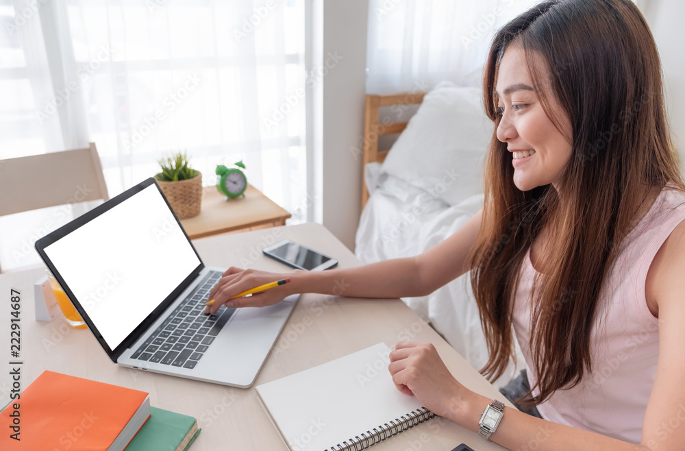 Poster asian woman use laptop and writing on paper sheet working online on table at home.mock up template device screen.Digital lifestyle concept.clipping path screen.