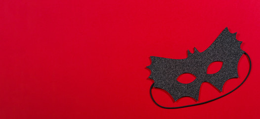 Black halloween mask on red background