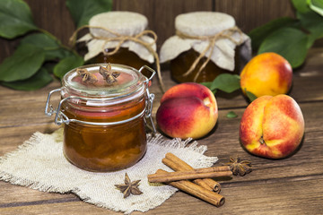 Food. Homemade canned fruit in cans. Fruit peach jam and fresh ripe peaches on the background of a wooden table in a rural style