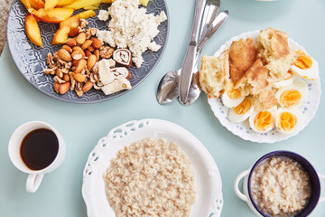 Light healthy Breakfast with oatmeal and coffee on a turquoise table. Hercules, nuts, fruit, boiled eggs, bread, coffee. Tableware. Healthy food. 