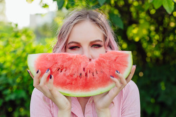 Beautiful young woman with pink hair enjoying watermelon