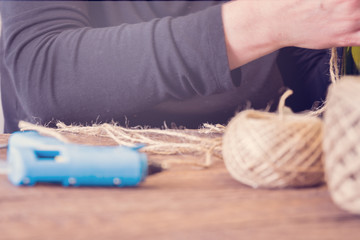 Woman decorating a bottle from wine with an ecological twine. Rustic style, handmade craft. Gift for christmas and other celebrations. Crafting process. Selective focus