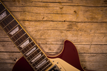Obraz premium Close-up of electric guitar lying on vintage wood background, with copy space