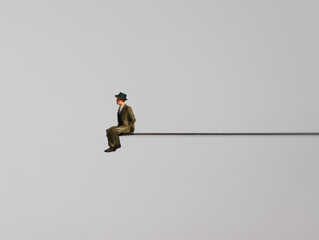A miniature man sitting on the edge of a precipice.