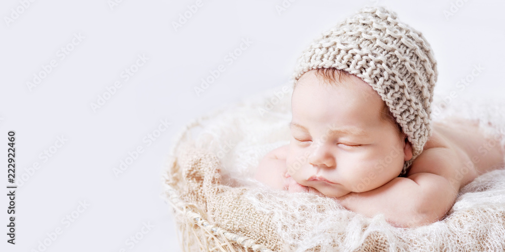 Wall mural sweet newborn baby sleeps. newborn boy folded handles in a basket. copyspace