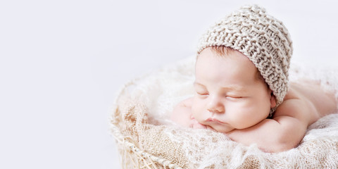 Fototapeta na wymiar Sweet newborn baby sleeps. Newborn boy folded handles in a basket. Copyspace