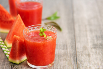 Watermelon smoothie in jars with fresh watermelon slices on gray wooden background. Copy space